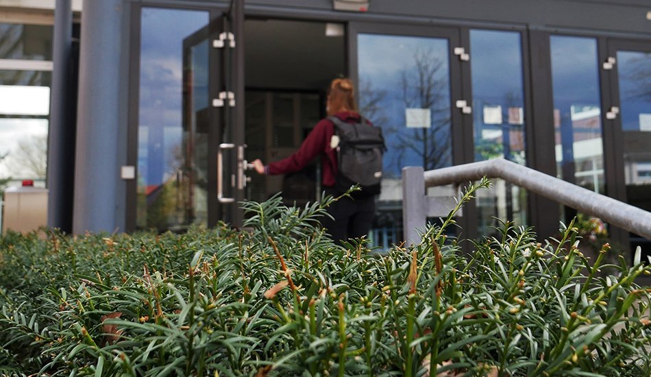 Studentin geht durch den Haupteingang der Universität