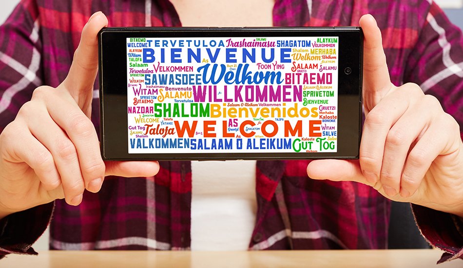 Person hält Tablet, dass Willkommen in verschiedenen Sprachen zeigt