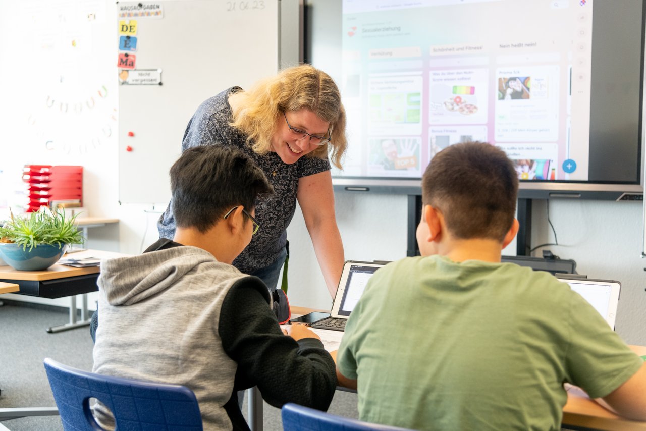 Lehrerin gibt Schülern Hinweise am Tablet.