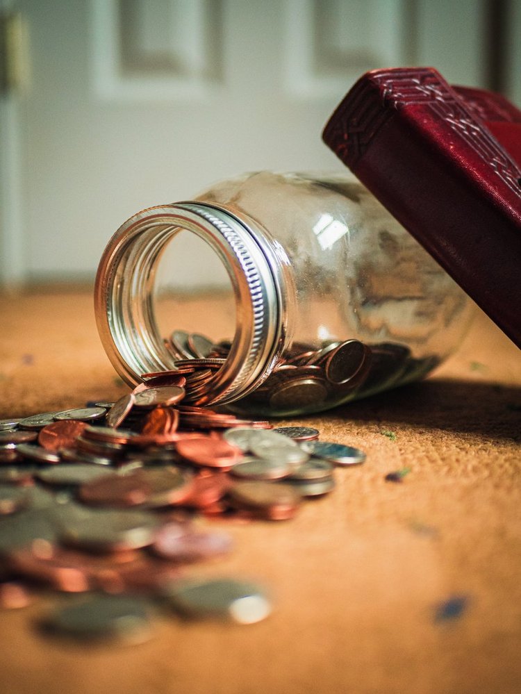 Ein Foto von einem umgekippten Glas mit Münzen (Quelle: Unsplash)