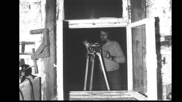 Durch das geöffnete Fenster der Webstube filmt ein Kameramann die Arbeitsschritte der Leinenweberei.