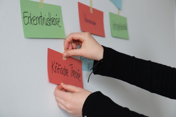 Workshop - Eine Person pinnt einen Zettel an eine Wand