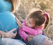 Mädchen streichelt Bauch einer schwangeren Frau