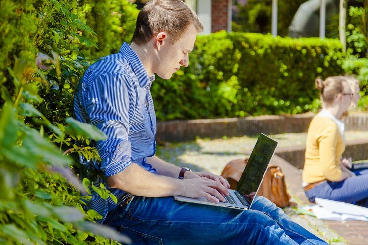 zeigt einen Studenten am Laptop auf dem Campus