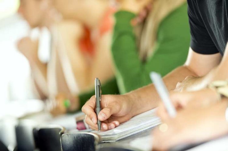 Studierende notieren sich etwas auf Papier