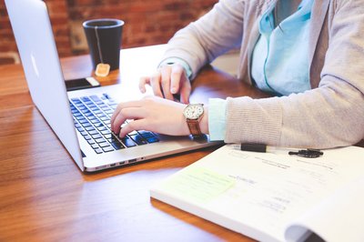Schreibtisch mit einer Person, die an einem Laptop arbeitet. Schreibtisch mit einer Person, die an einem Laptop arbeitet.