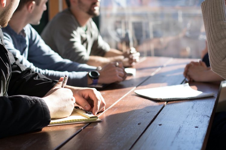 eine Gruppe von Menschen, die zusammen am Tisch sitzen (Quelle: Unsplash)