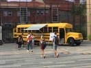 Der MO•KU•LAB Bus mit Markise und geöffneten Türen steht im Innenhof des Schloßes. Einige Menschen gehen auf den Bus zu. 