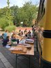 Eine Gruppe von Kindern sitzt neben dem Bus und betrachtet Ergebnisse