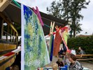 Einsatz auf dem Hoffest beim Sonnenhof e.V. – Ergebnisse des Workshops Papierbögen trocknen an einer Wäscheliene, im Hintergrund sieht man bastelnde Kinder an einem Tisch neben einem amerikanischen Schulsbus