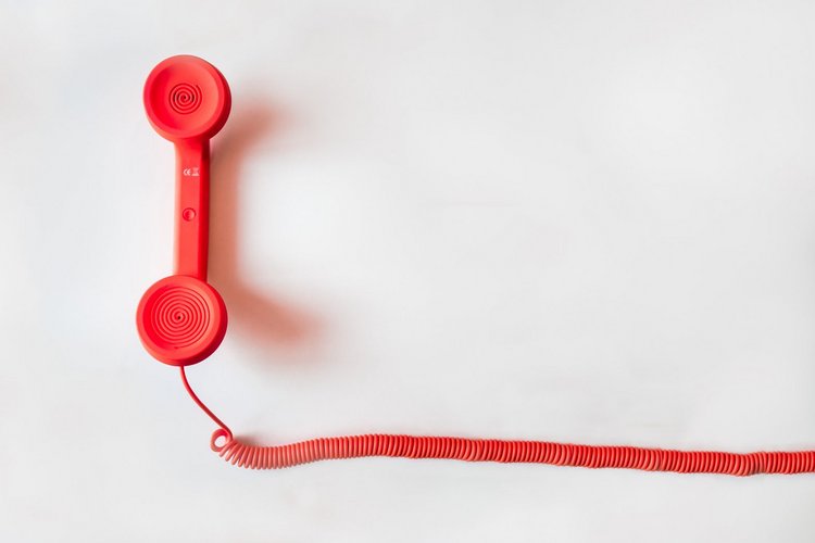 Roter Telefonhörer mit Telefonschnur auf weißem Hintergrund