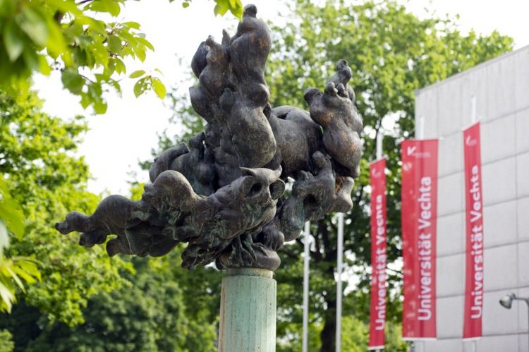 Skulptur vor dem Haupteingang, im hintergrund sind Fahnen der Universität zu sehen