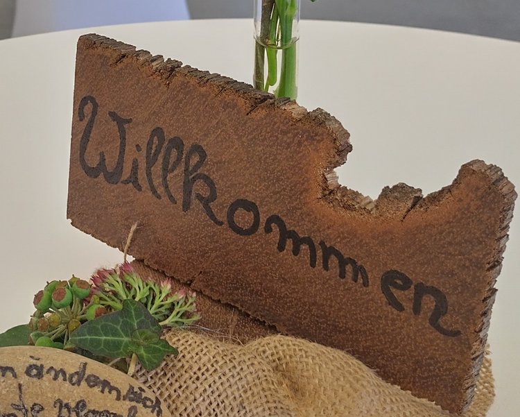Holzschild einer Tischdekoration mit der Aufschrift Willkommen.