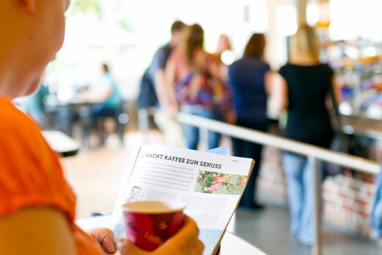 Person lesend mit Kaffee in der Hand