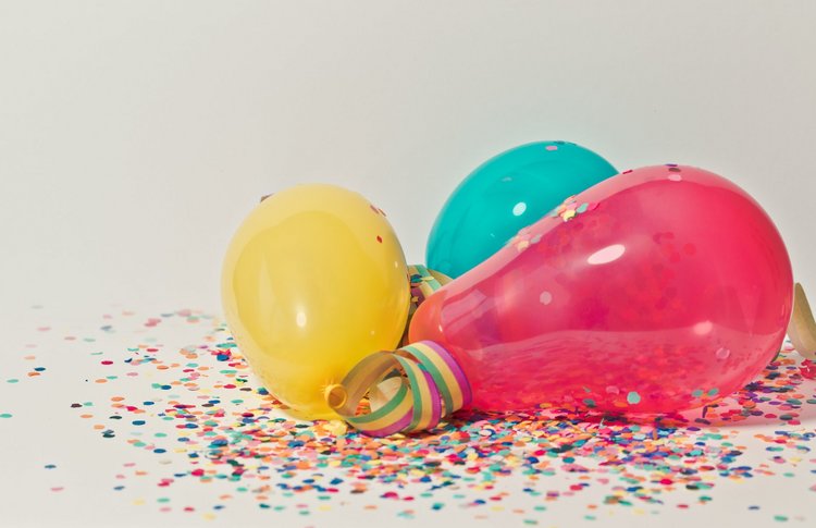 Luftballons liegen auf Konfetti mit Luftschlangen