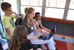 Eine Studentin hilft Kindern bei der Bearbeitung ihrer Aufnahmen am Computer