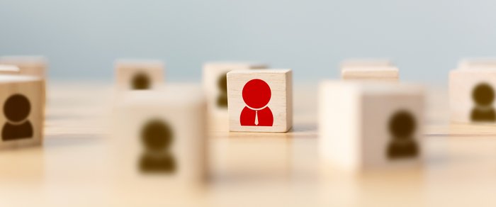 Hand of a businessman chooses a wooden cube block with icon people standing out from the crowd. Successful business team leader concept