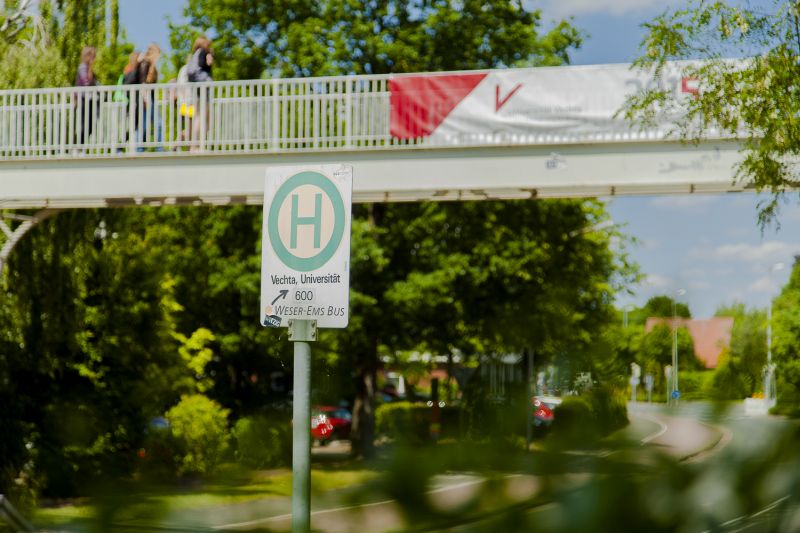 Brücke mit Universitätsbanner und Bushaltestellenschild
