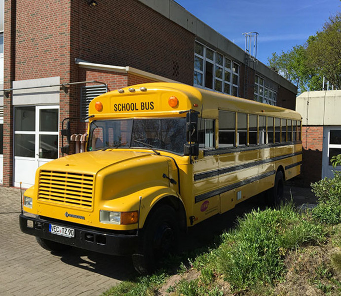 Gelber, amerikanischer Schulbus stehend vor einem Gebäude. 