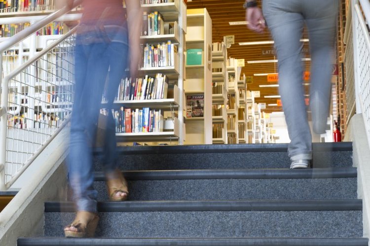 Zwie Personen gehen eine Treppe in der Bibliothek hinunter
